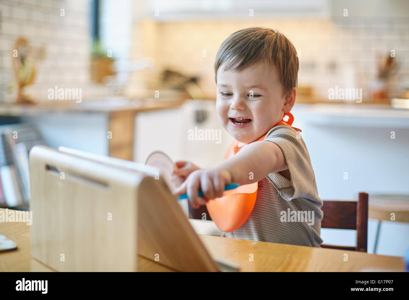 Baby Junge saß am Tisch zeigt auf digital-Tablette Stockfoto