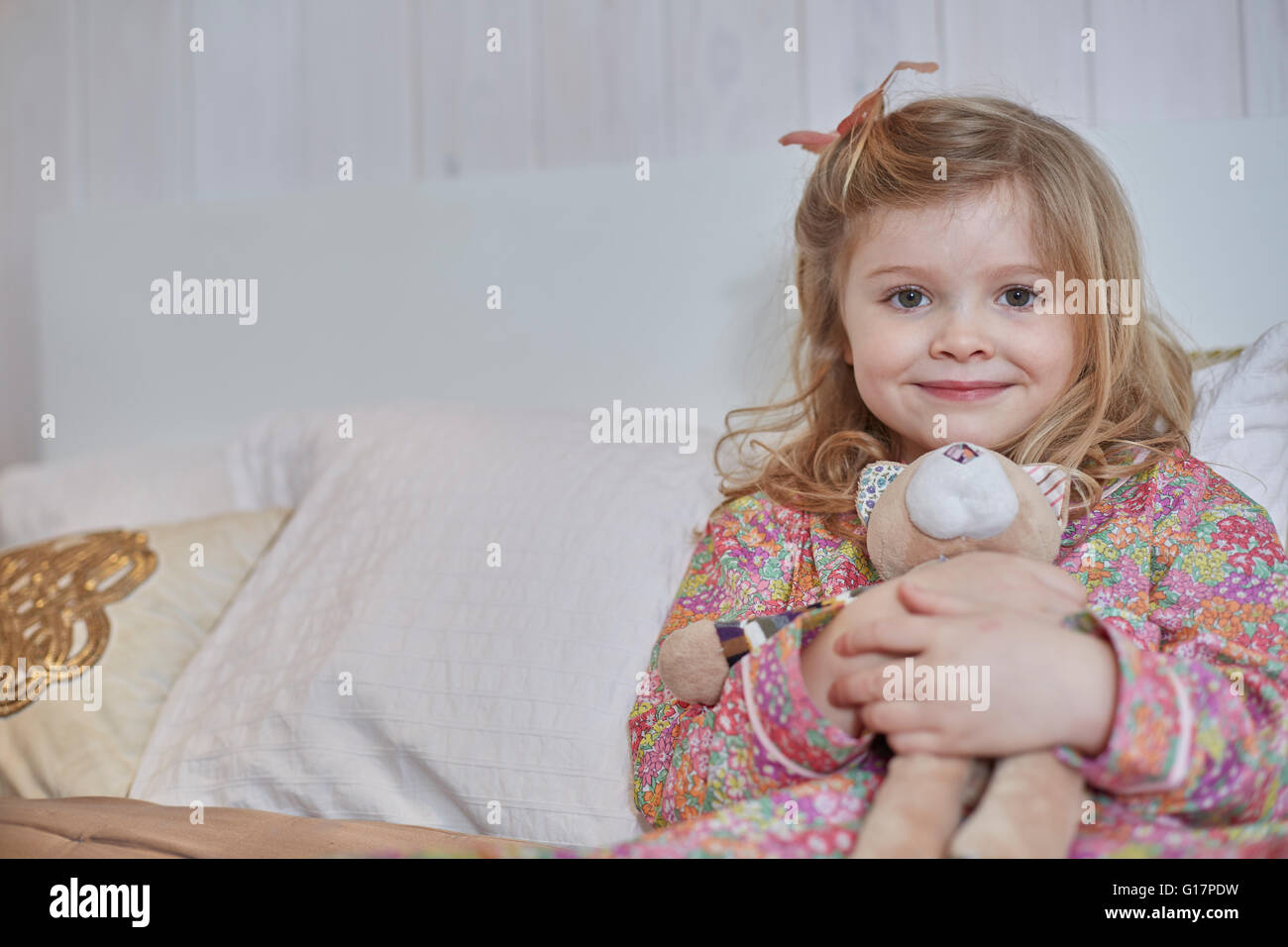 Mädchen im Schlafanzug umarmt Teddybär im Bett Stockfoto