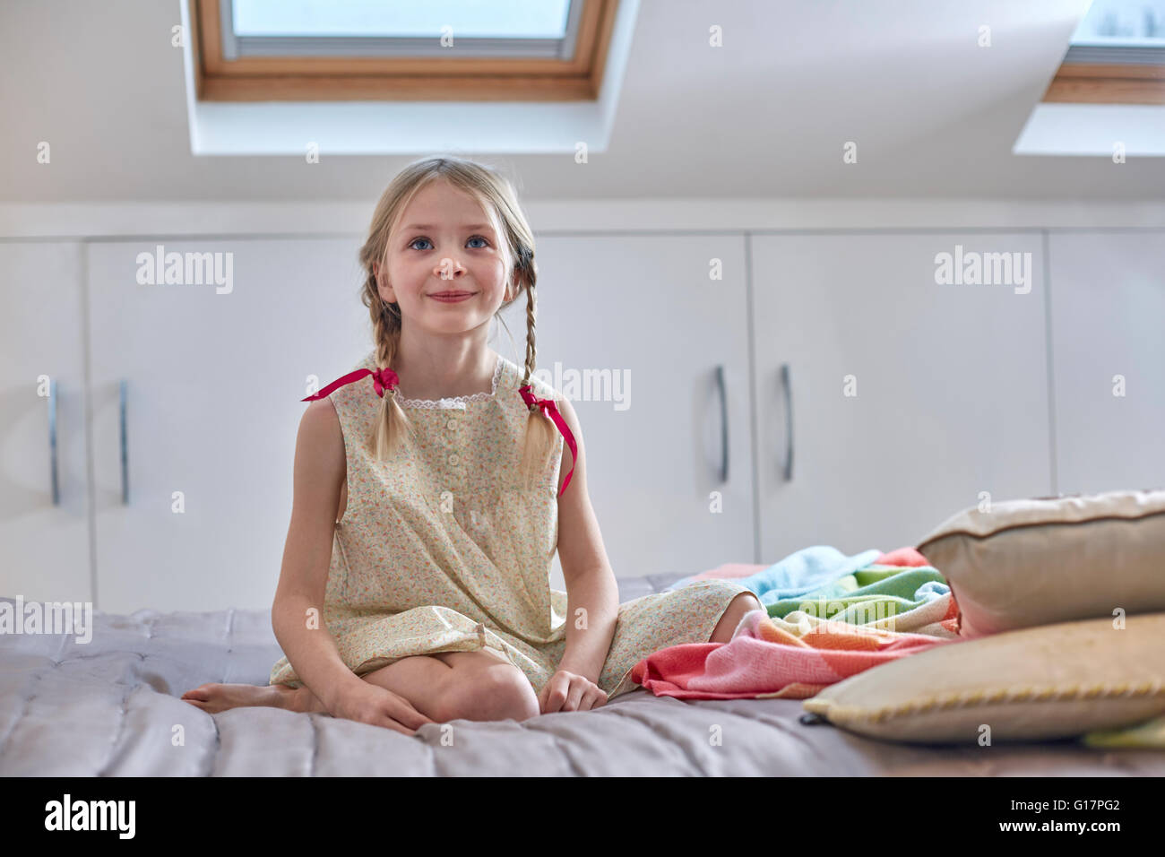 Mädchen sitzen auf Bett im Loft-Zimmer Stockfoto