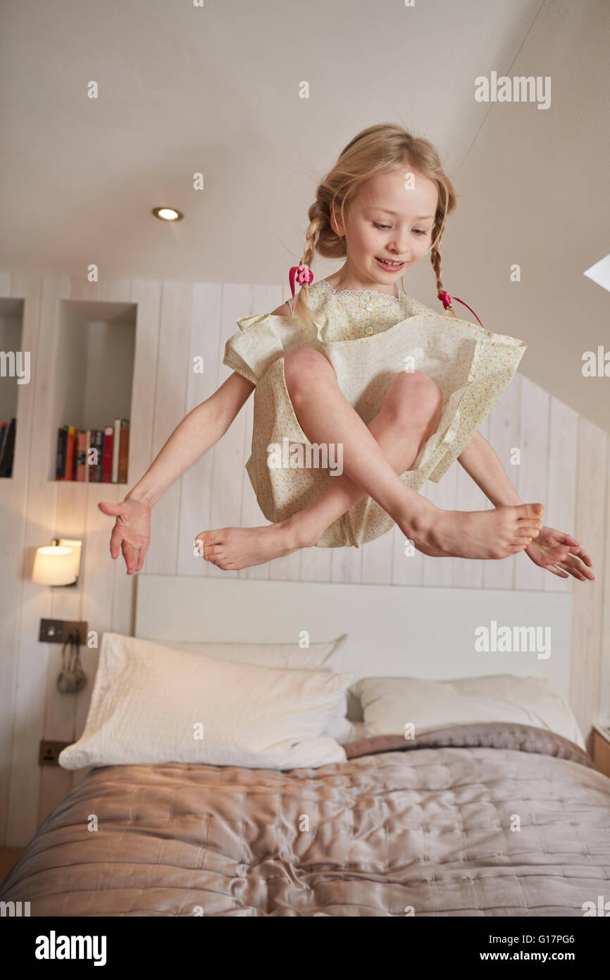 Mädchen schwebt über Bett Stockfoto