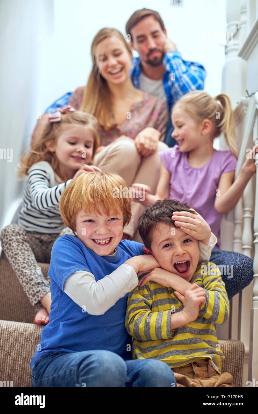 Glückliche Eltern und Kinder sitzen auf der Treppe Stockfoto