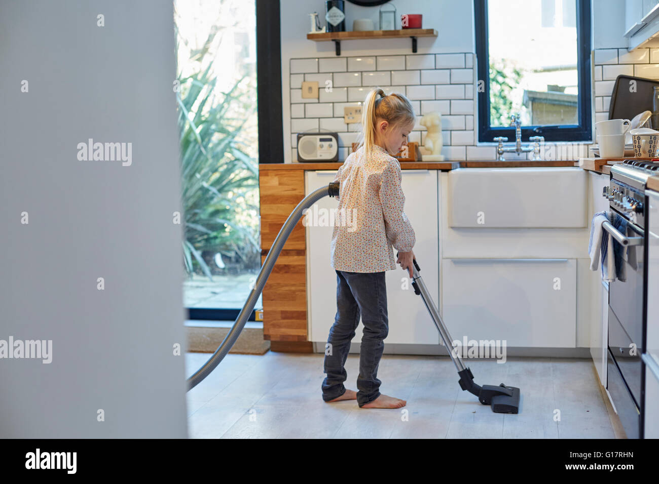 Mädchen saugen Küchenboden Stockfoto