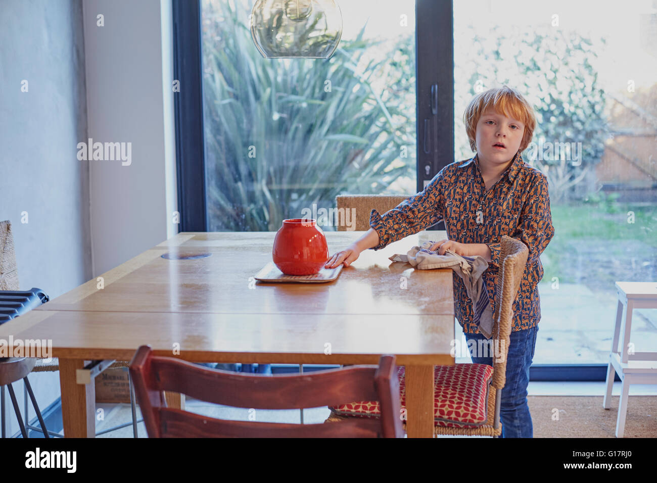 Jungen wischen und Aufräumen Esstisch Stockfoto