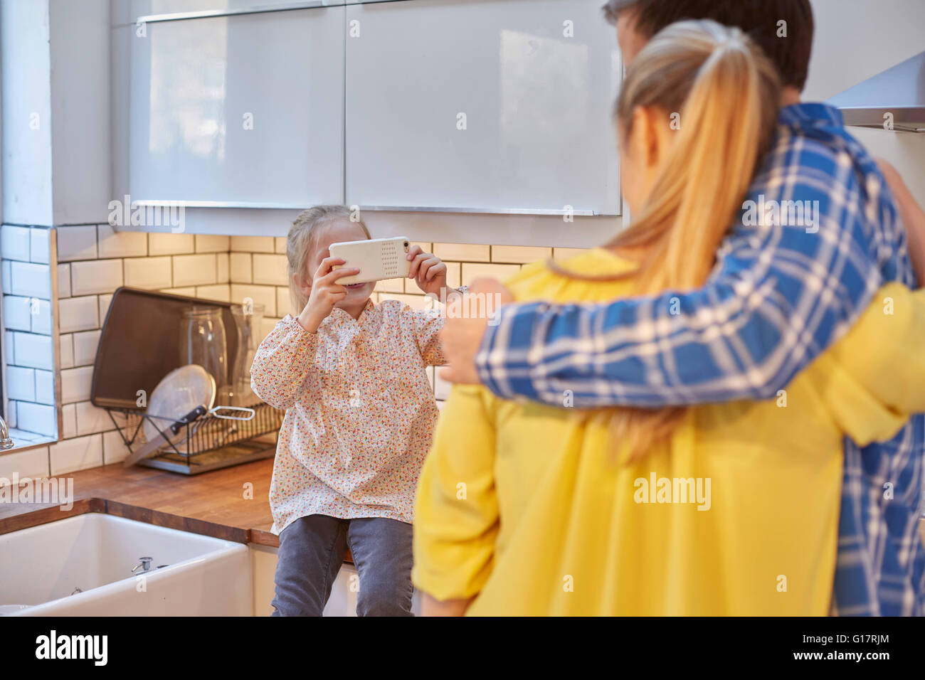 Tochter nehmen Foto von Eltern in Küche Stockfoto