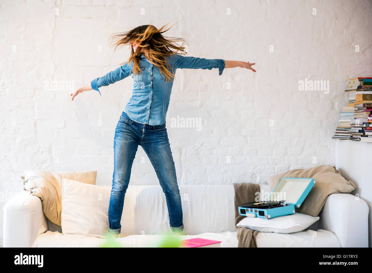 Junge Frau auf Sofa tanzen und schütteln ihr Haar Stockfoto