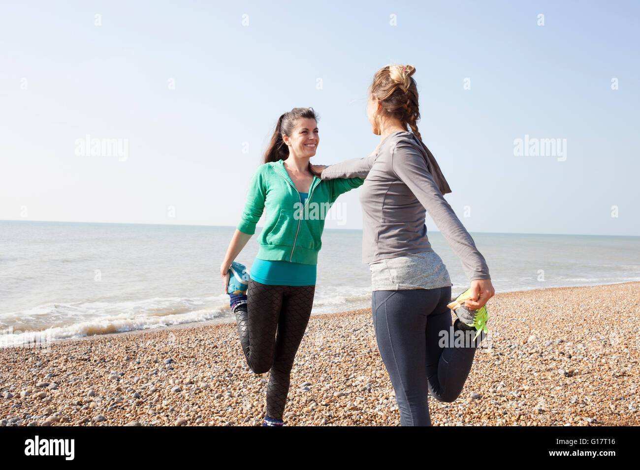 Zwei Frauen, training, stehen auf einem Bein am Strand von Brighton Stockfoto