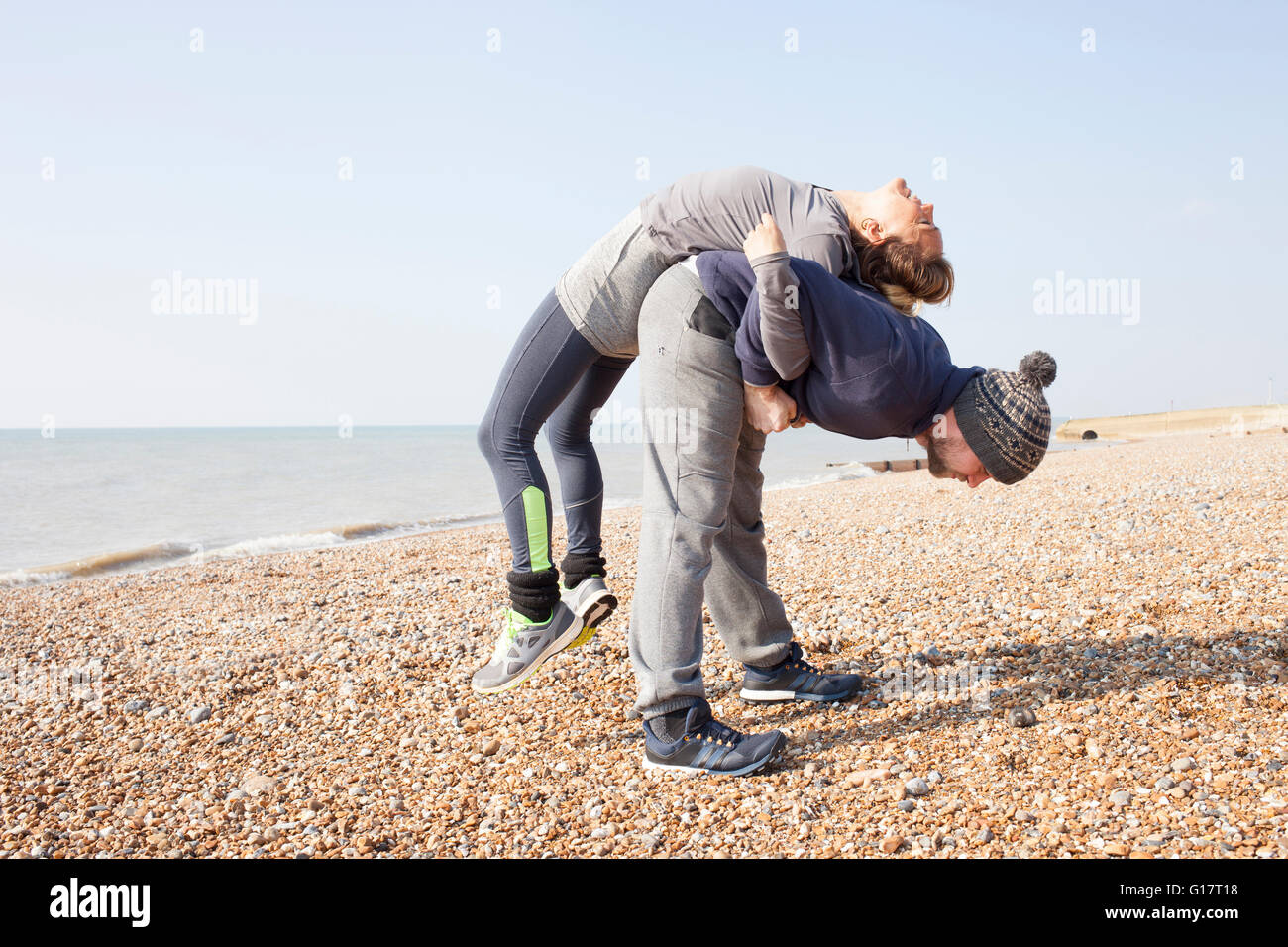 Mann und Frau Aufwärmen, Training, Rücken an Rücken heben auf Brighton beach Stockfoto