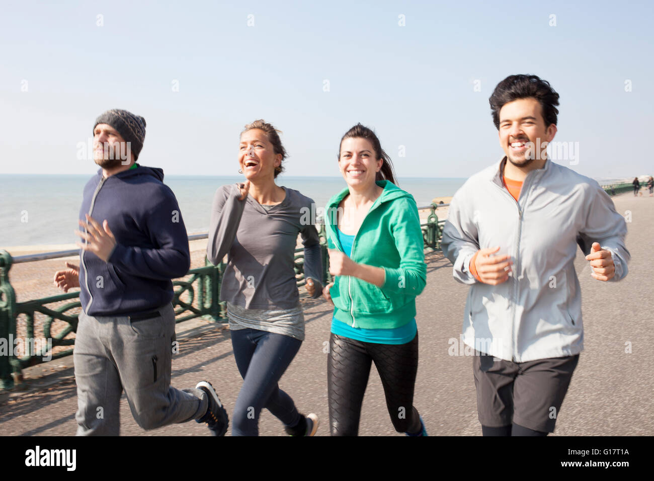 Männliche und weibliche Läufer laufen am Strand von Brighton Stockfoto