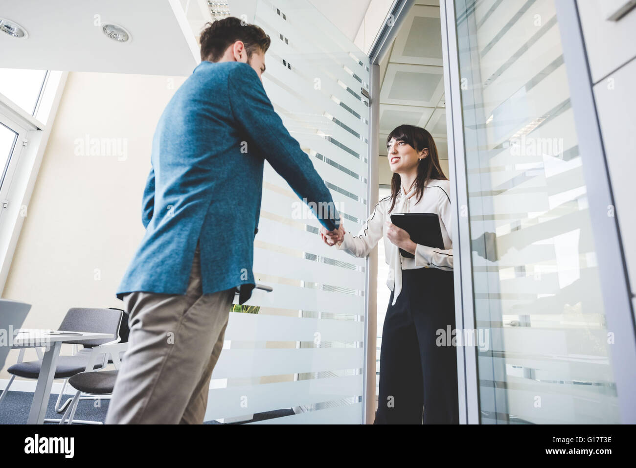 Junge Geschäftsfrau und Client Händeschütteln im Büro Stockfoto