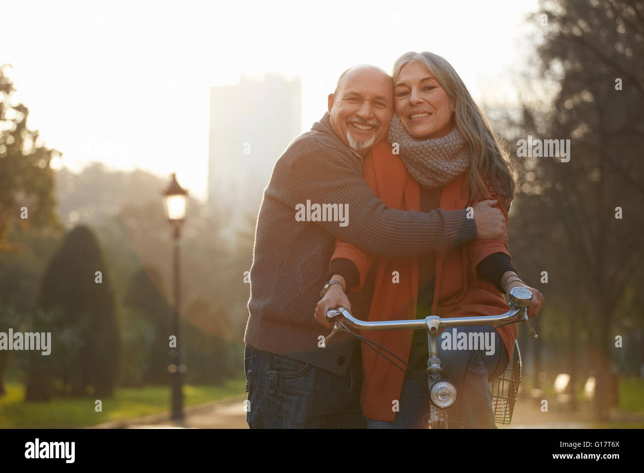 Mann umarmt Frau auf Fahrrad, Blick auf die Kamera zu Lächeln Stockfoto