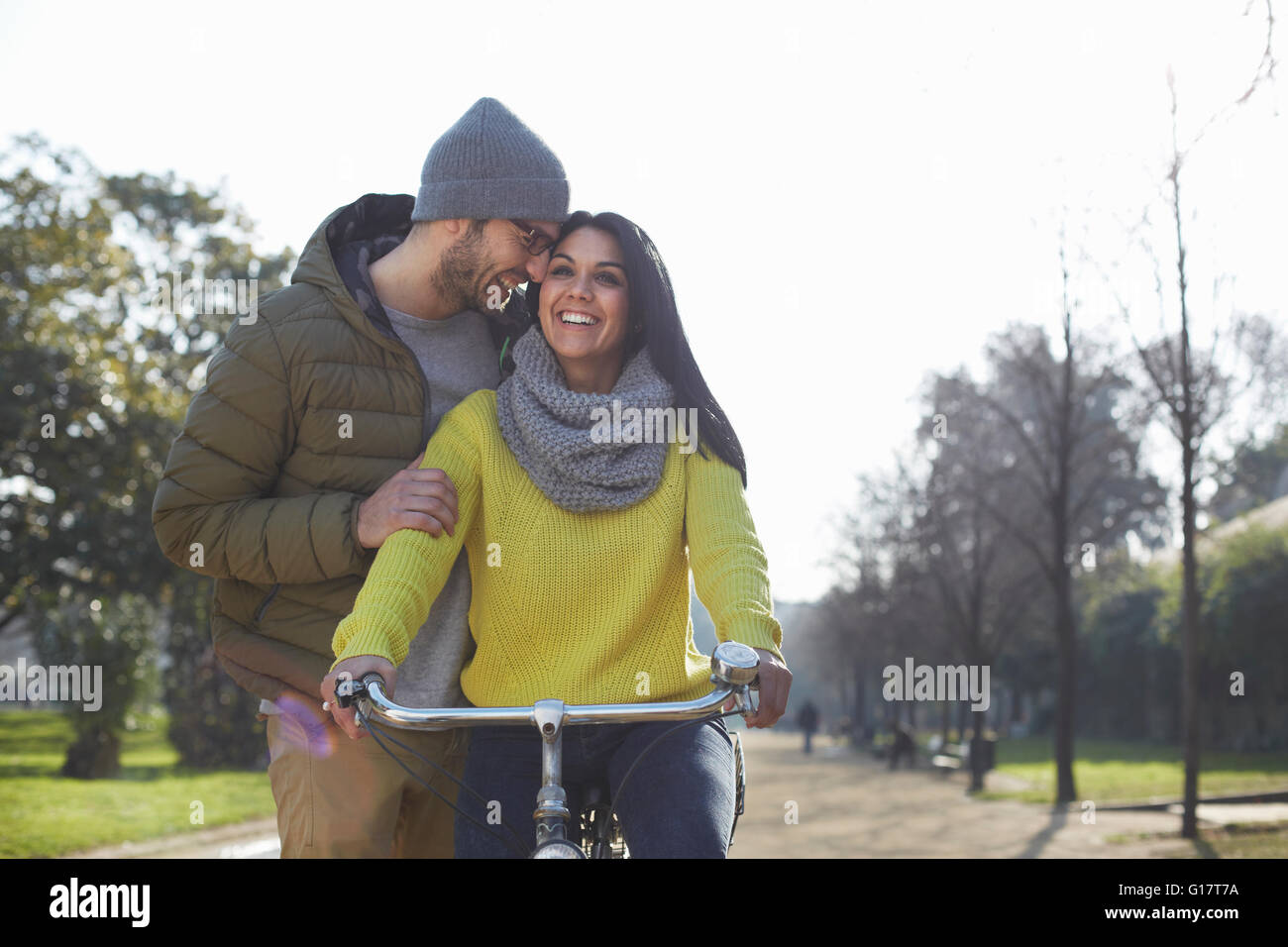 Mitte erwachsener Mann umarmt lächelnd Mitte Erwachsene Frau auf Fahrrad im park Stockfoto