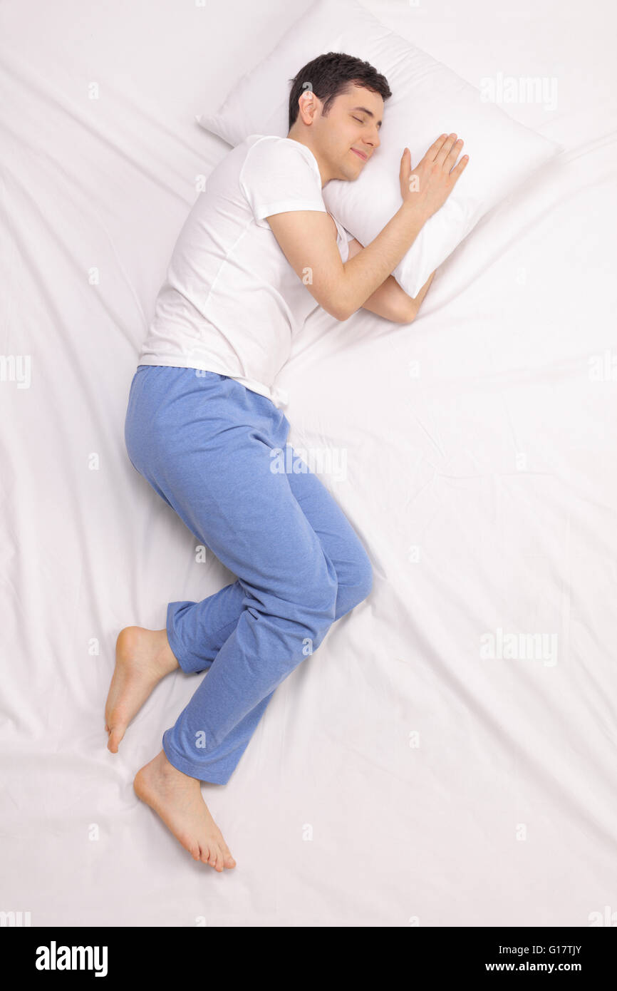 Vertikale Schuss von einem ruhigen jungen Mann auf einem bequemen Bett schlafen Stockfoto