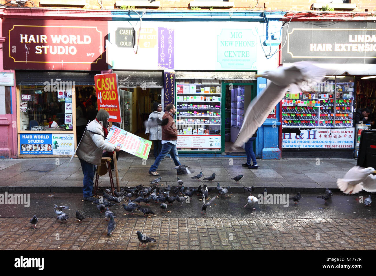 Straßenszene, Moore Street, Dublin, Irland: ein Mann mit einer Sandwichplatte füttert die Vögel Stockfoto