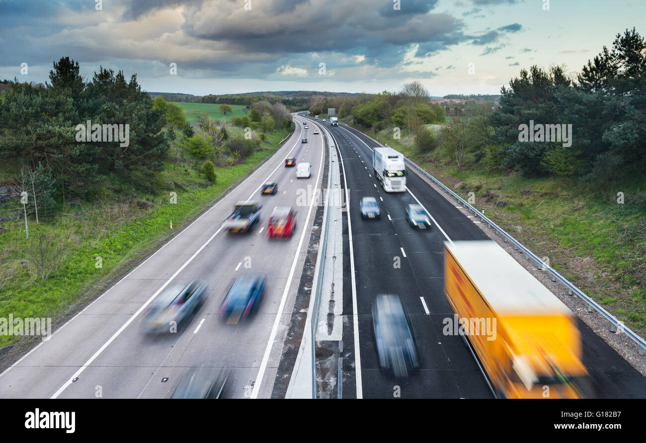 Autos in Bewegung auf Dual Lane Autobahn unter Frühlingsgrün Felder Stockfoto