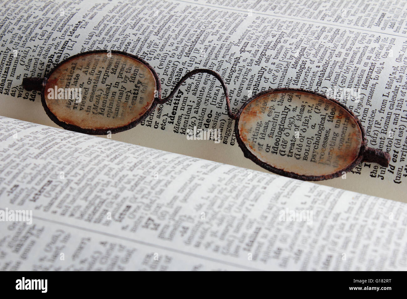 Antiker Lesebrille ruht auf einer offenen Wörterbuch-Seite. Stockfoto