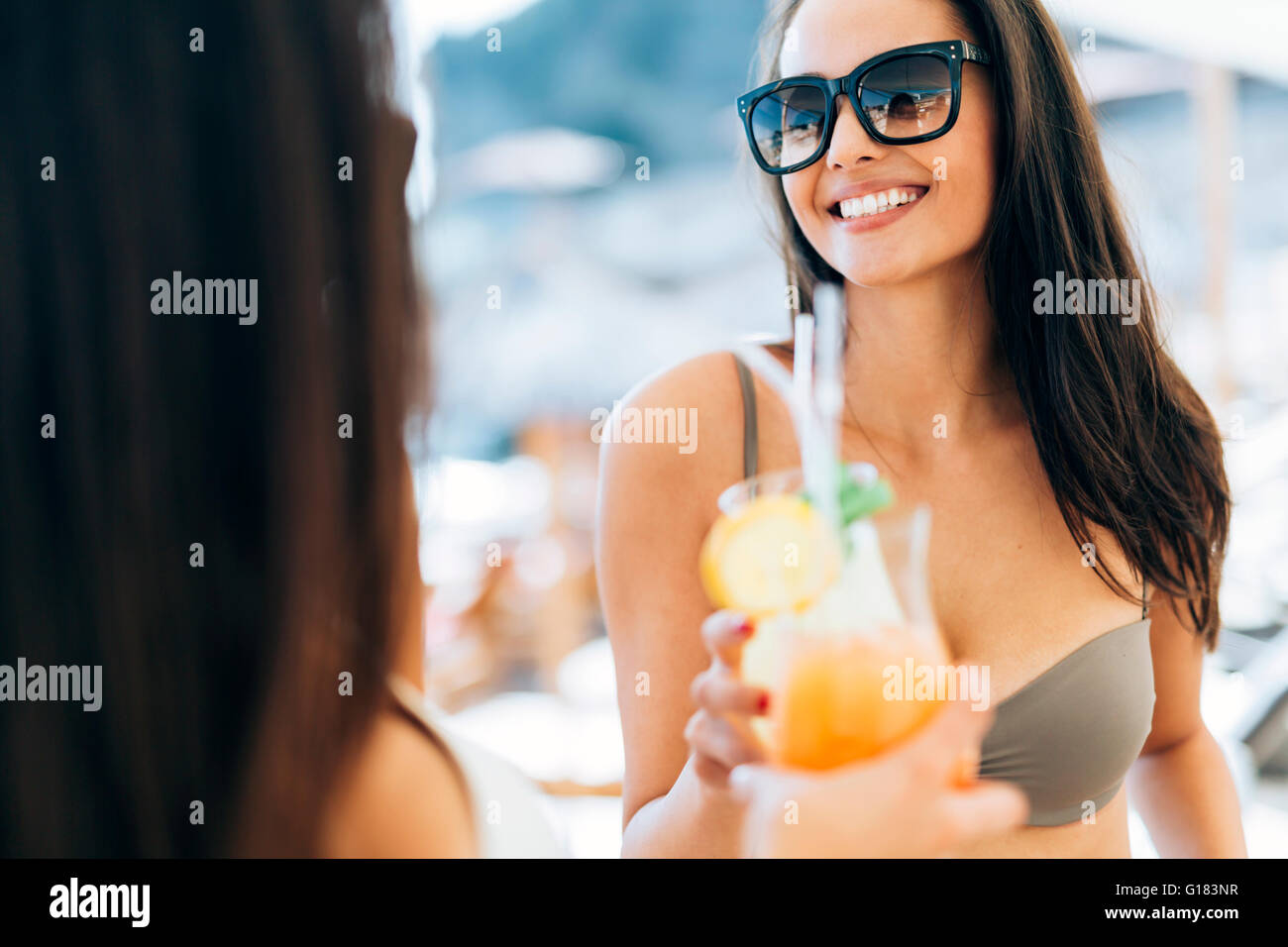 Fröhliche Freundinnen im Sommer Cocktails trinken und lächelnd Stockfoto