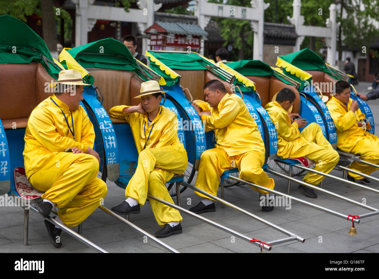Gelb gekleidet Rikscha Fahrer eine entspannte Pause von ihrer Arbeit in der Stadt Nanjing in China ruhen Stockfoto