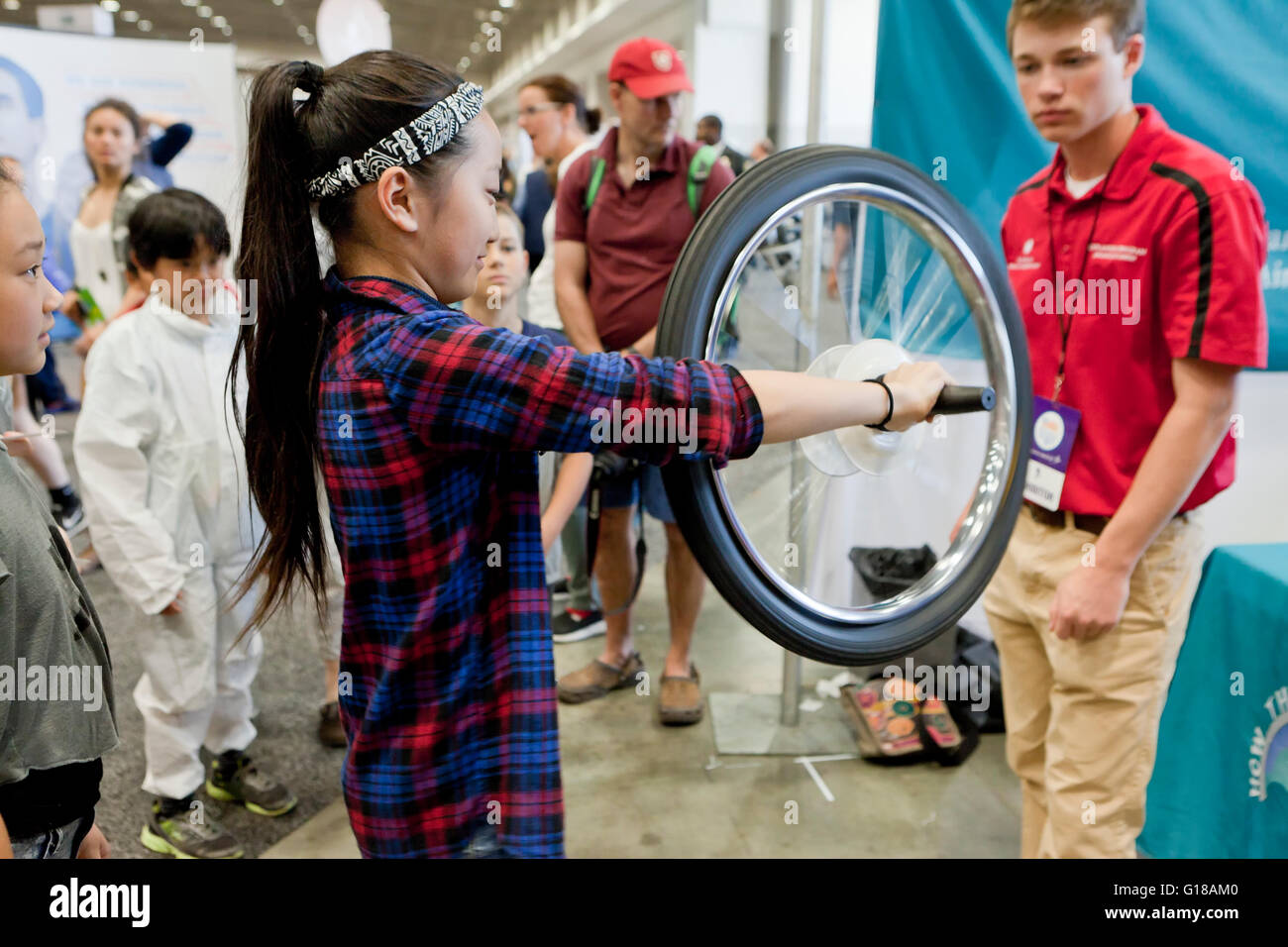 Junges Mädchen lernen Physik der Kreisel mit einem Fahrrad-Rad an einer Wissenschaftsmesse - USA Stockfoto