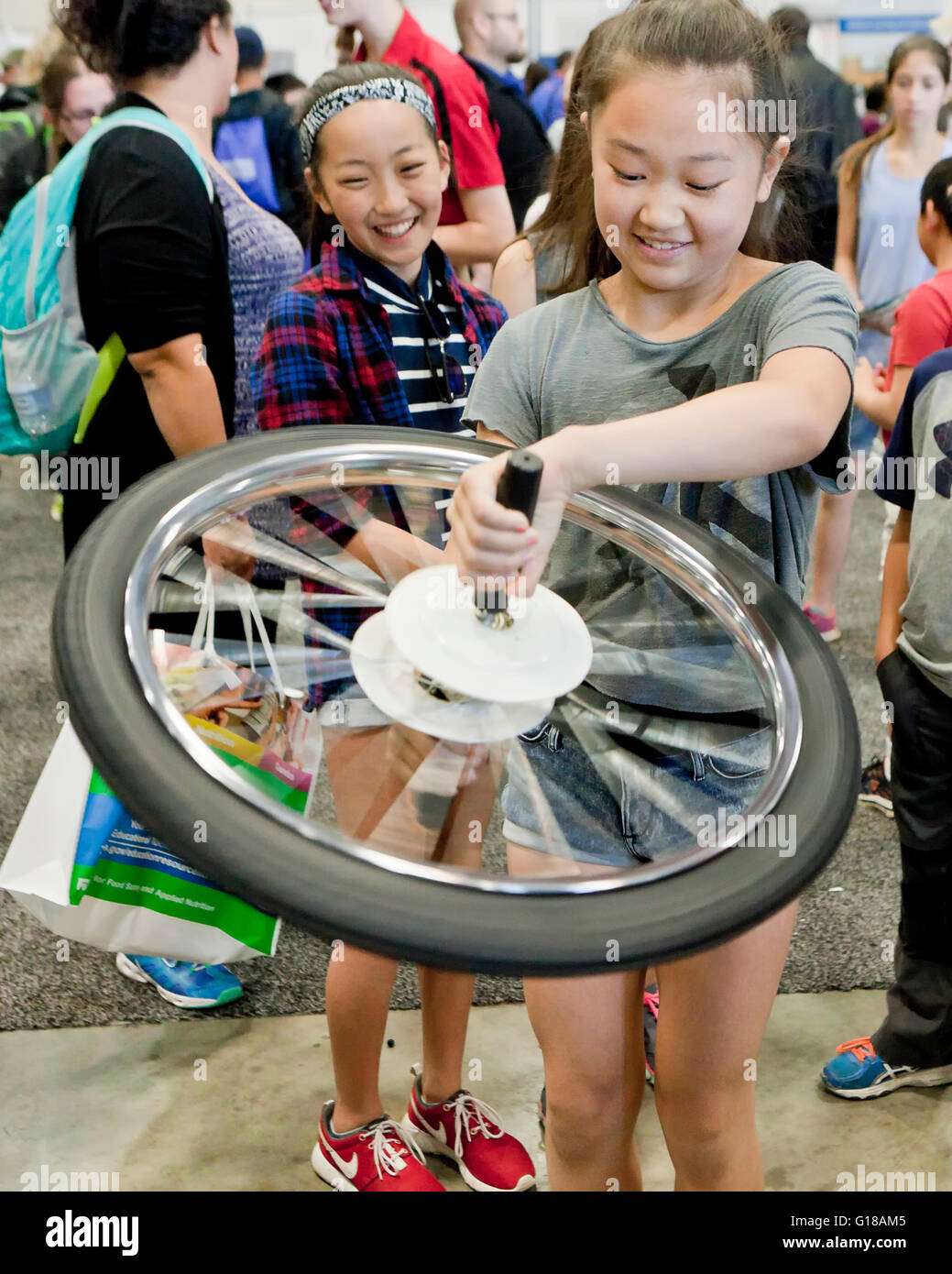 Junges Mädchen lernen Physik der Kreisel mit einem Fahrrad-Rad an einer Wissenschaftsmesse - USA Stockfoto