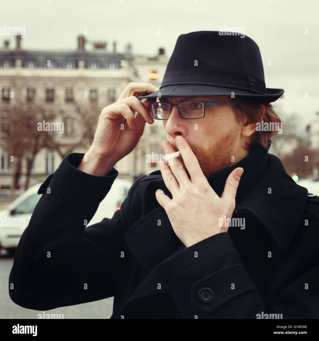 Attraktive bärtiger Mann tragen Hut Rauchen auf der Straße in europäischen Stadt Stockfoto