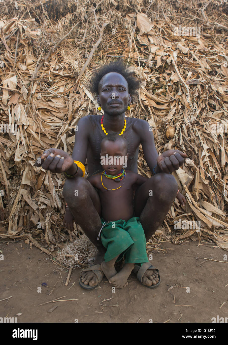 Dassanech Stamm-Vater und Sohn sitzen vor ihrem Haus, Omo-Tal, Omorate, Äthiopien Stockfoto