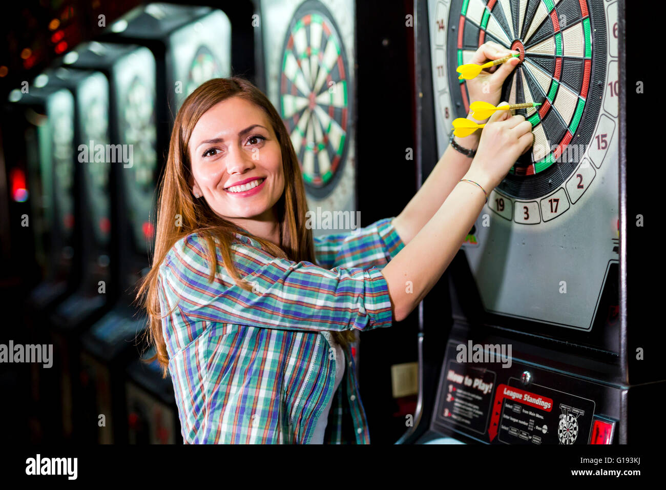 Junge schöne Frau in einem Club Dart spielen und Lächeln Stockfoto