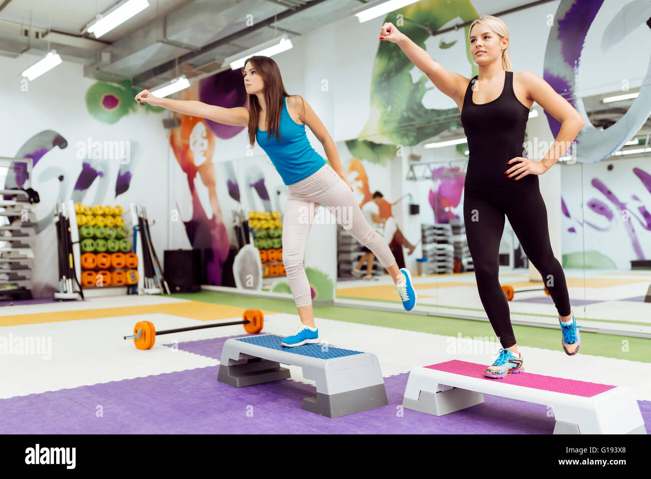 Schöne Frauen, die Aerobic im schönen Fitnessclub trainieren Stockfoto