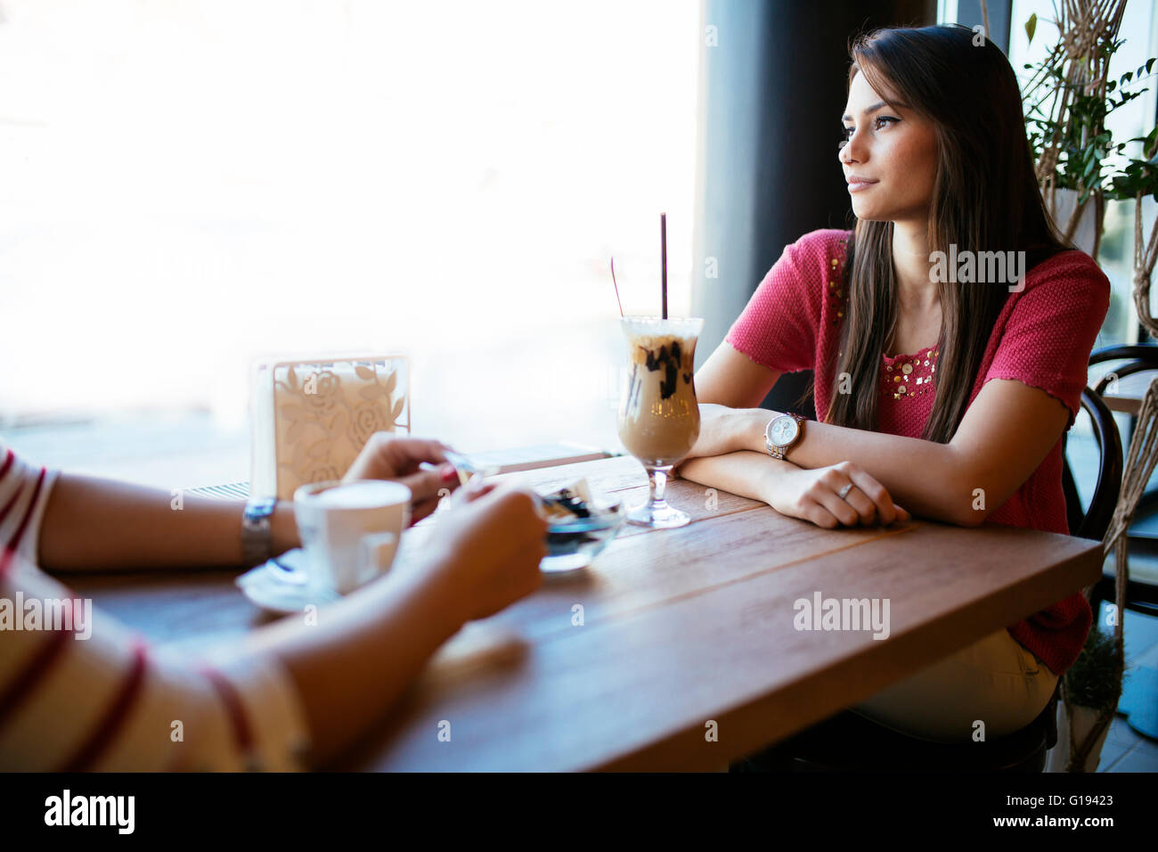 Schöne Frau im Gespräch mit Freund im Restaurant beim Kaffeetrinken Stockfoto