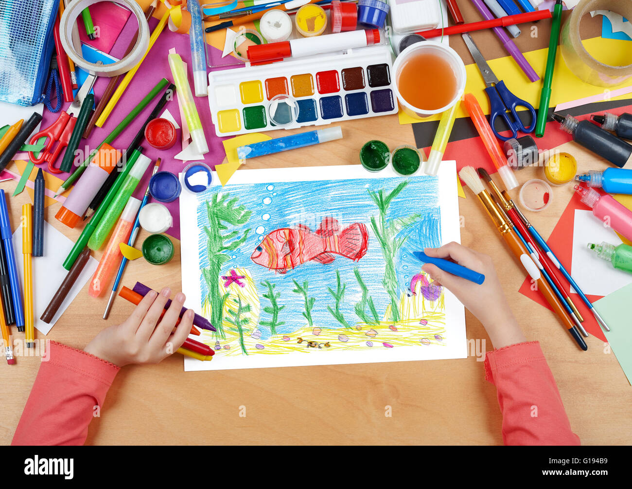 roter Fisch unter Wasser, Krabbe auf Meeresboden, Kind zeichnen, Draufsicht Hände mit Bleistift Gemälde Bild auf Papier, Kunstwerk am Arbeitsplatz Stockfoto