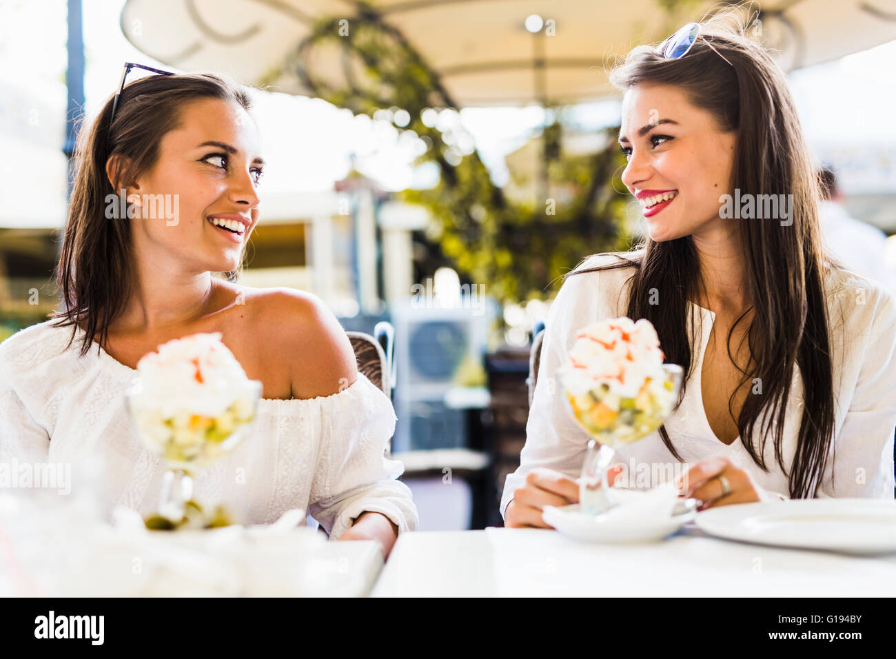 Zwei schöne junge Frauen Lächeln auf den Lippen und einen Obstsalat in ein Restaurant im freien Stockfoto