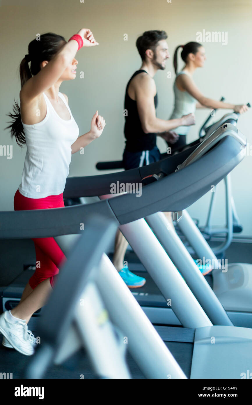 Junge und schöne Dame laufen auf einem Laufband und wischt Schweiß von ihrer Stirn Stockfoto