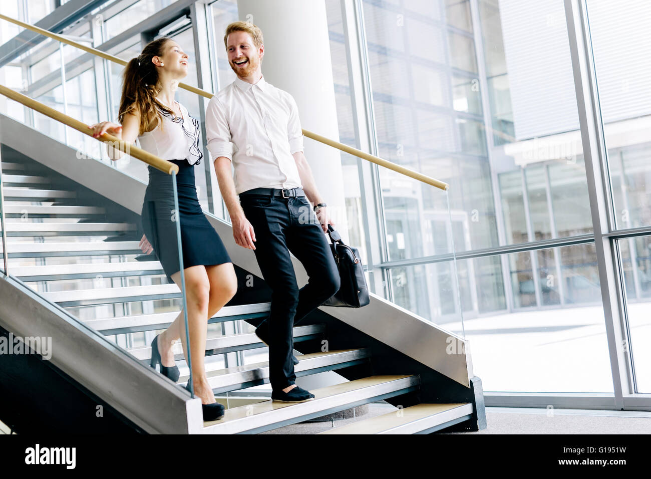 Geschäftskollegen sprechen auf Treppen und flirten während lächelnd Stockfoto