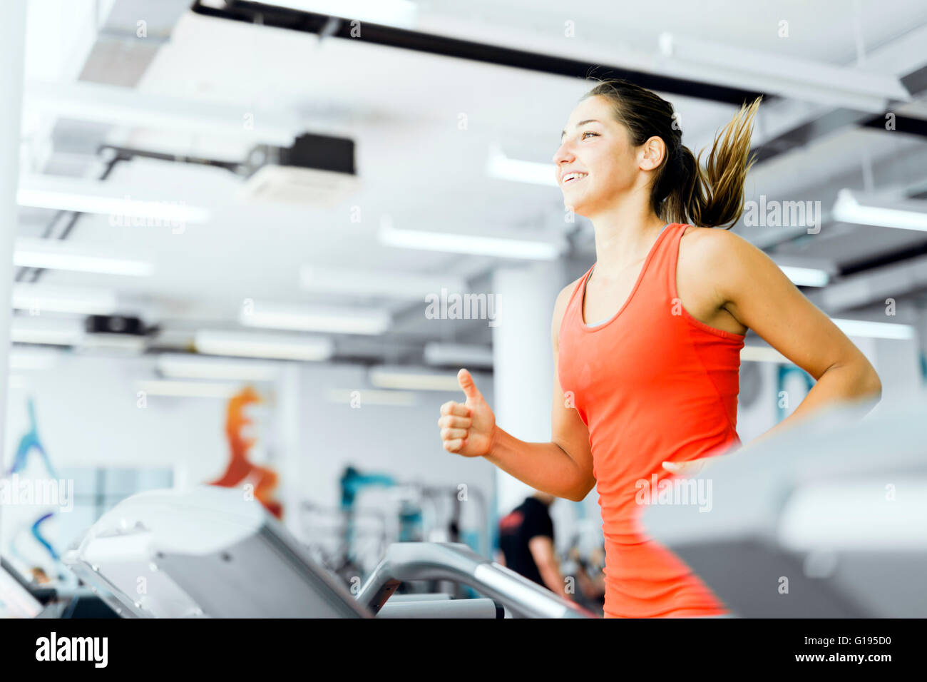 Schöne junge Frau laufen auf einem Laufband im Fitnessstudio und lächelnd Stockfoto