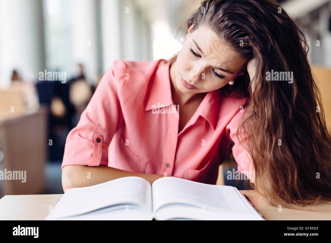 Weibliche Studenten studieren und lesen in einer Bibliothek aber ist eine harte Zeit Verständnis des Materials Stockfoto
