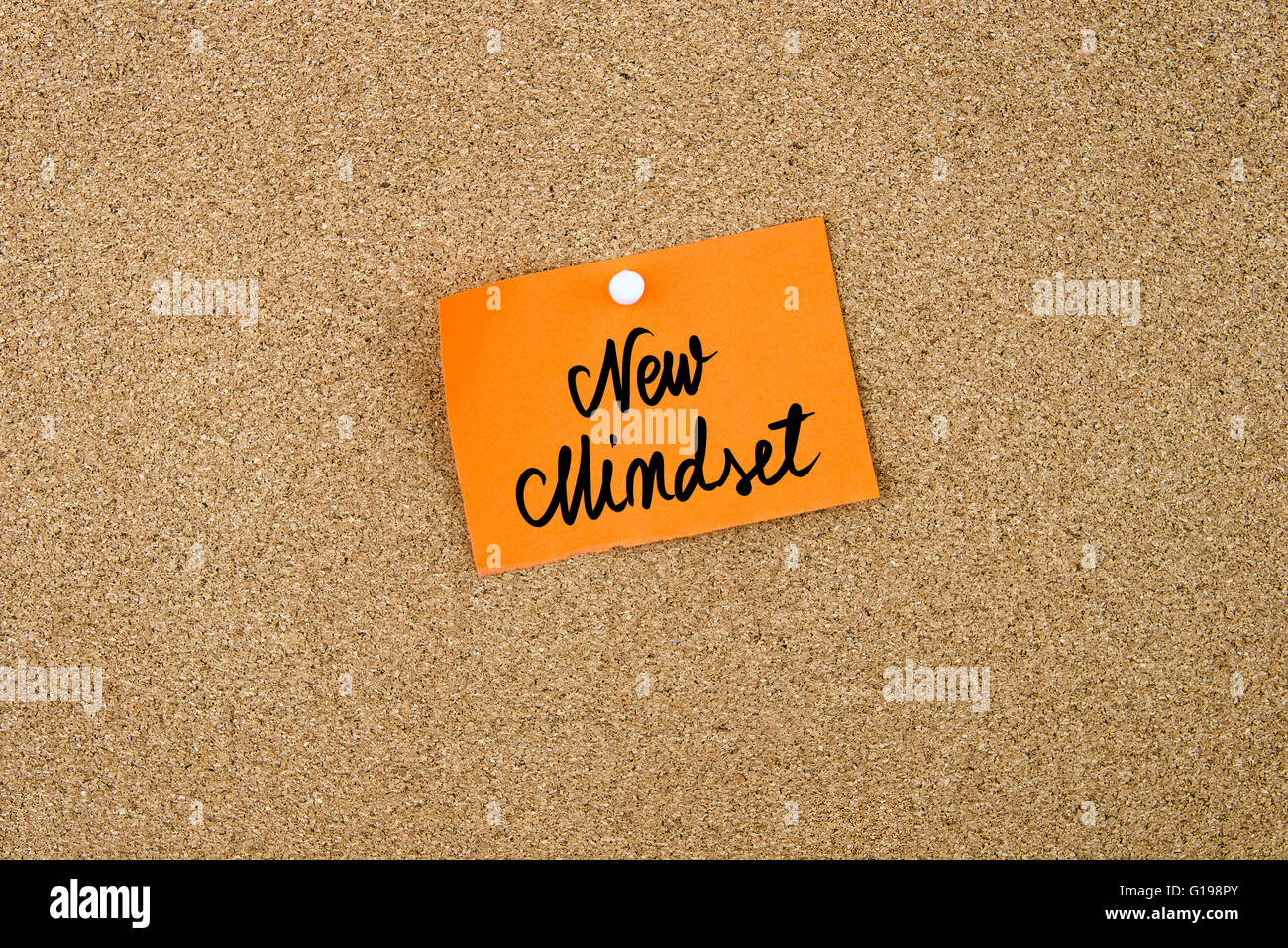 Neue Denkweise geschrieben am orange Papier-Schuldbrief angeheftet auf Pinnwand mit weißen Reißzwecken textfreiraum verfügbar Stockfoto