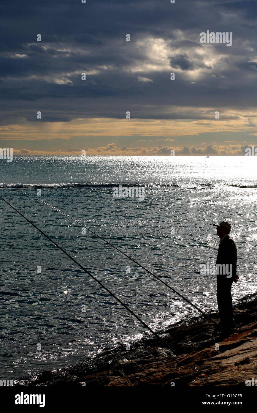 Costa Blanca Spanien Alicante Stadt Mann Angeln vom Felsen Playa del Postiguet Stockfoto