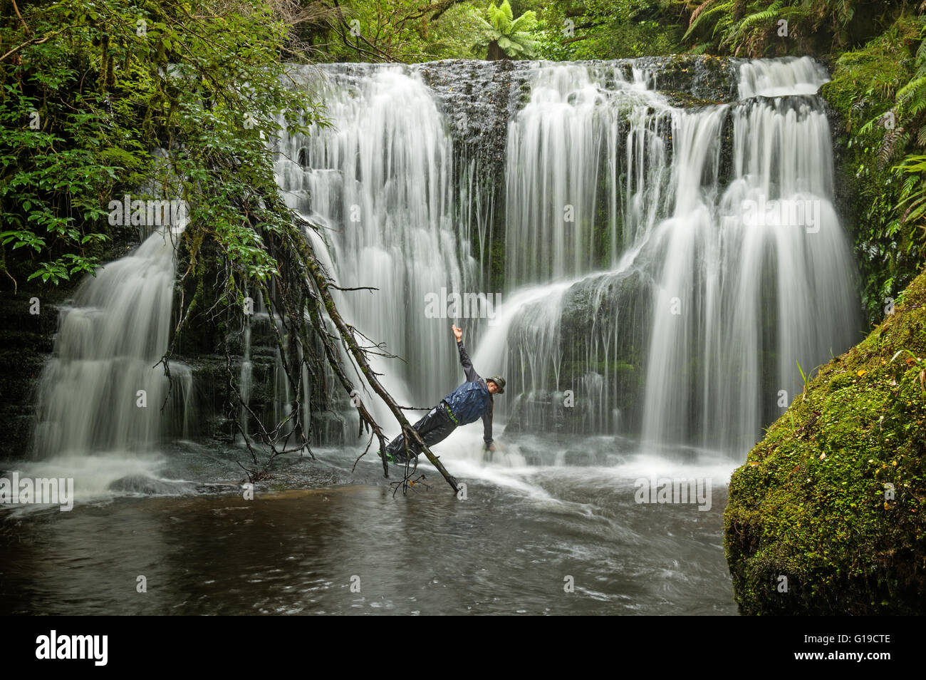 Langzeitbelichtung der Mann tut Yoga Pose Seite Planke in einem Wasserfall Stockfoto