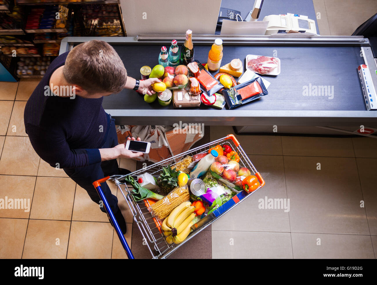 Junger Mann vor der Kasse im Supermarkt Stockfoto