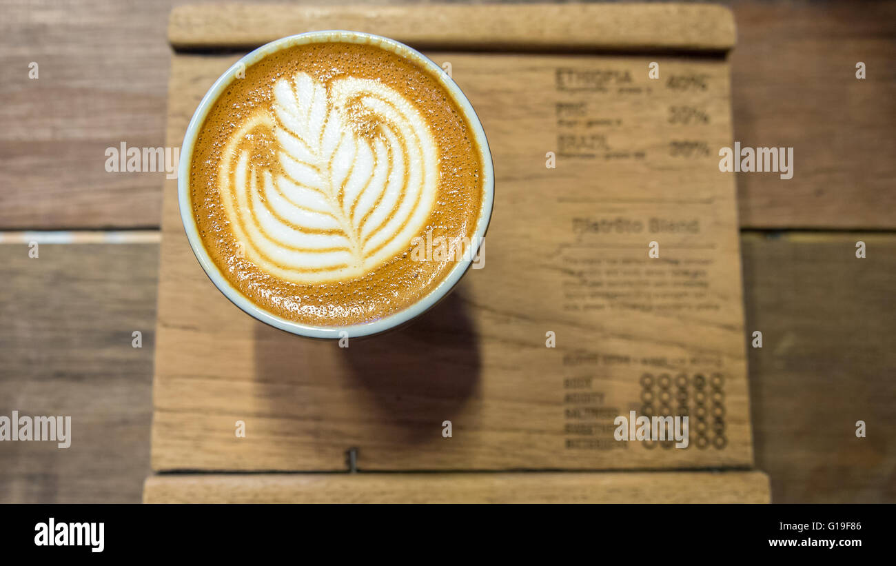 Kaffee mit weißen Blatt Latte Kunst auf Holzbrett Stockfoto