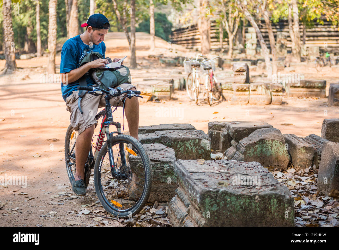 Ein Tourist auf dem Fahrrad suchen Sie nach Informationen über einen großen Reiseführer in der Nähe von Angkor Wat Tempel Stockfoto