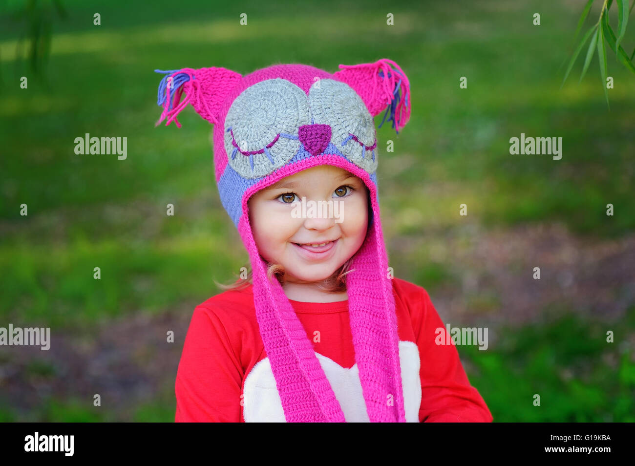 Niedliche kleine Mädchen auf der Wiese im Sommertag eine Strickmütze Eule Stockfoto