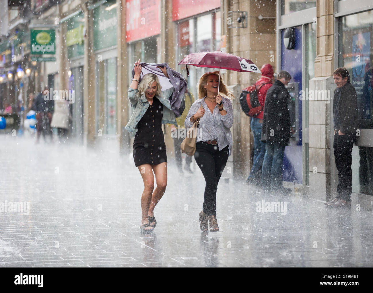 Zwei Frauen liefen eine Straße in Leicester, UK, in einen Regenschauer. Stockfoto