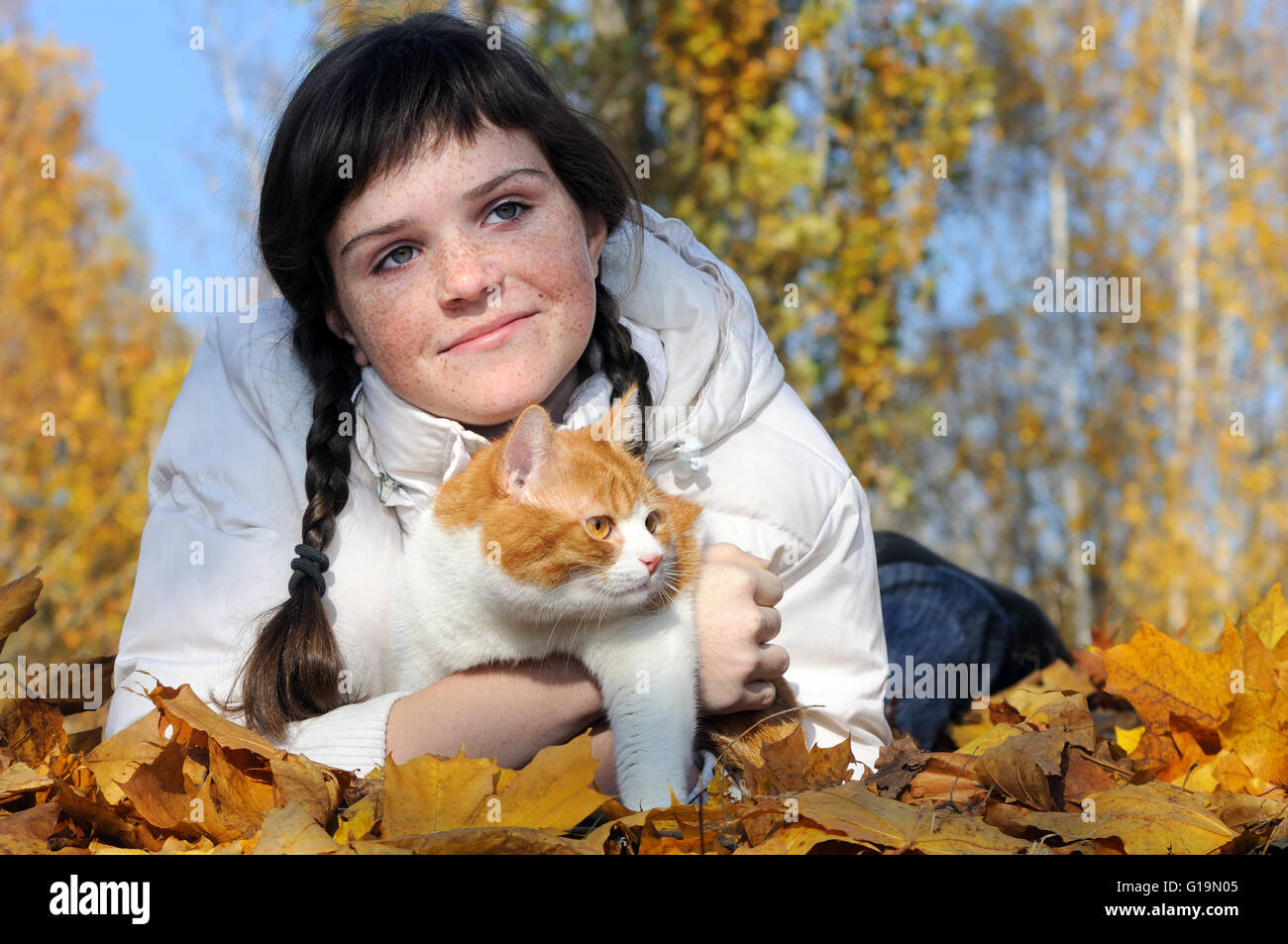 sommersprossige Teenager-Mädchen und Katze entspannend im Herbst park Stockfoto