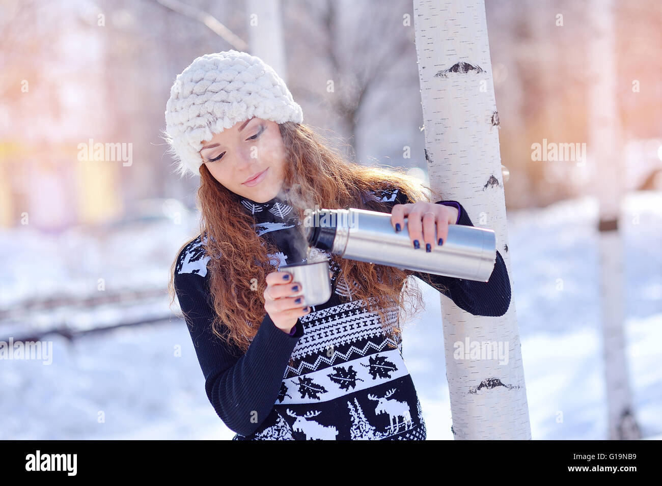 Mädchen trinken heißen Tee im Winterwald Stockfoto