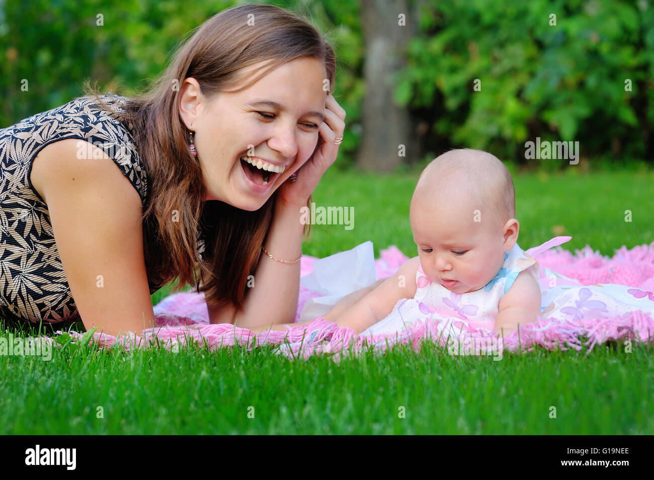 Glückliche Mutter und Baby Verlegung auf Wiese Stockfoto
