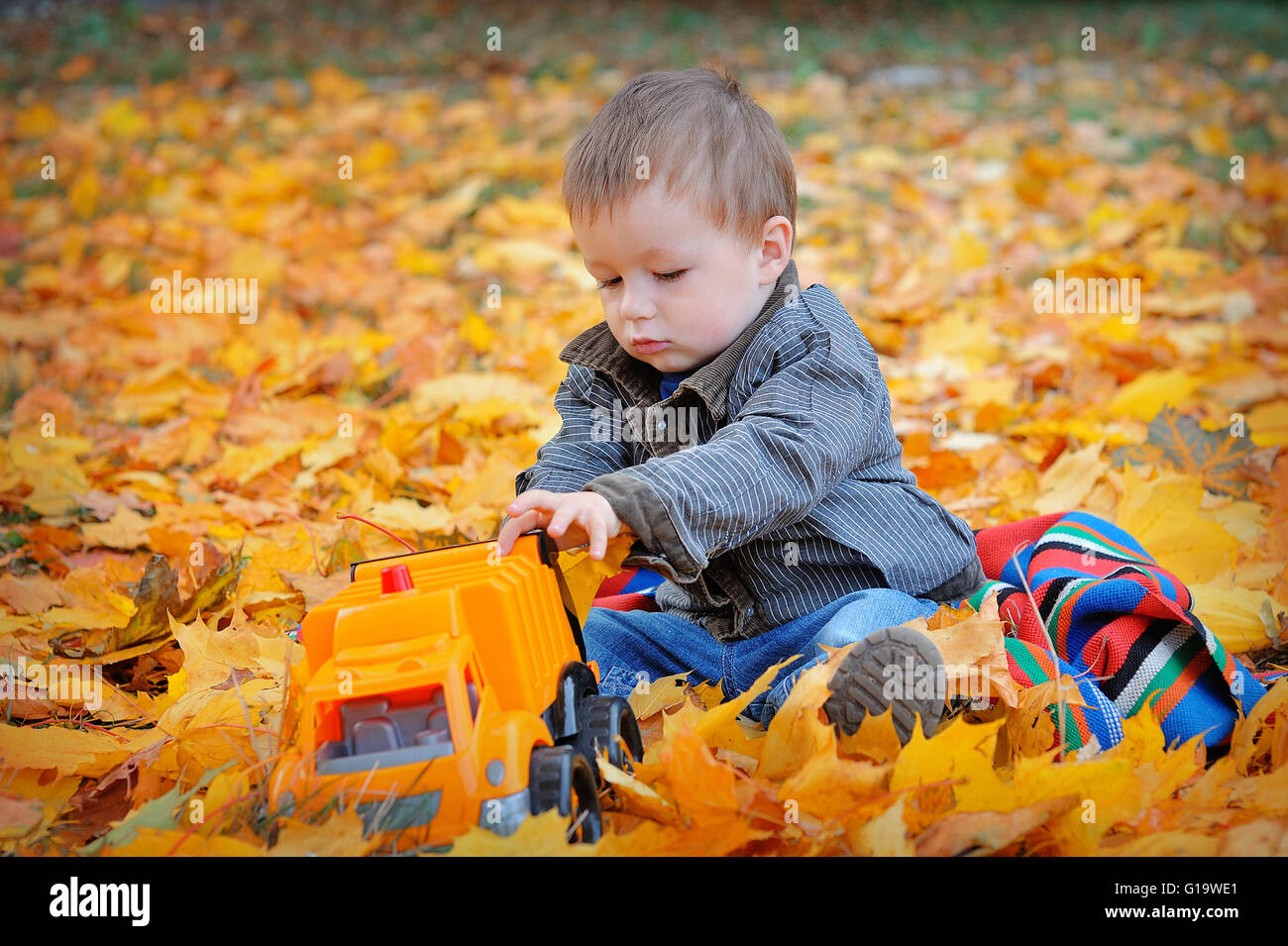 Jungen spielen Maschine gelbe Herbstfärbung verlässt Stockfoto