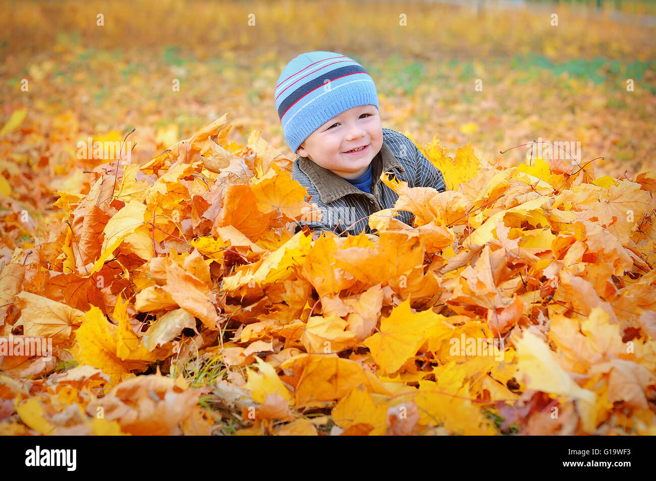 Glückliches Kind gelbe Herbstfärbung lässt im park Stockfoto