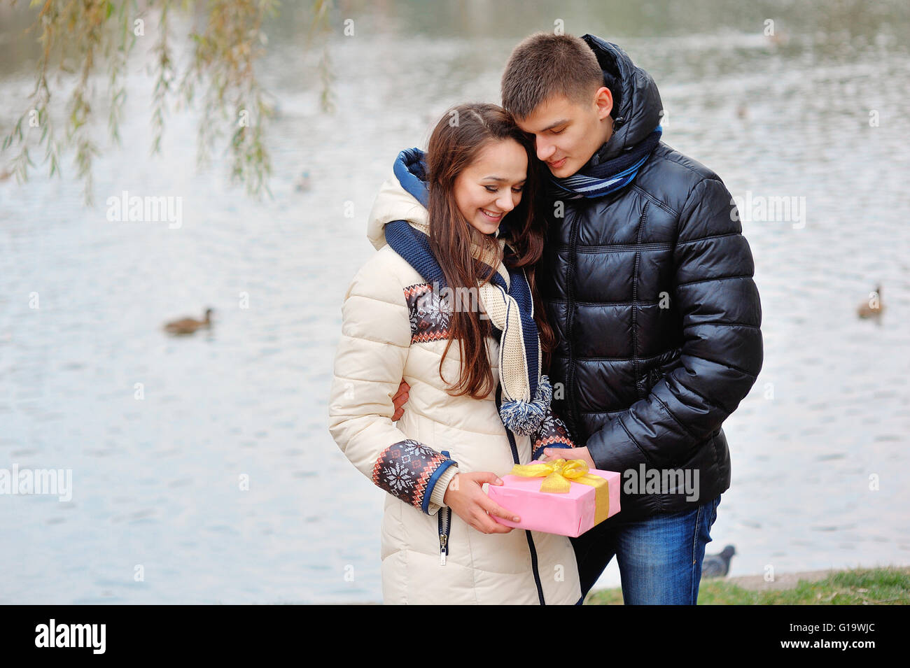 Der junge Mann gibt ein Geschenk, einem jungen Mädchen in das Café und Sie Stockfoto