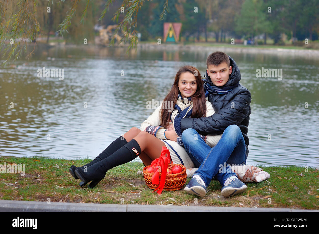 Jungen und Mädchen im Park auf einem Hintergrund von Wasser mit Äpfeln Stockfoto