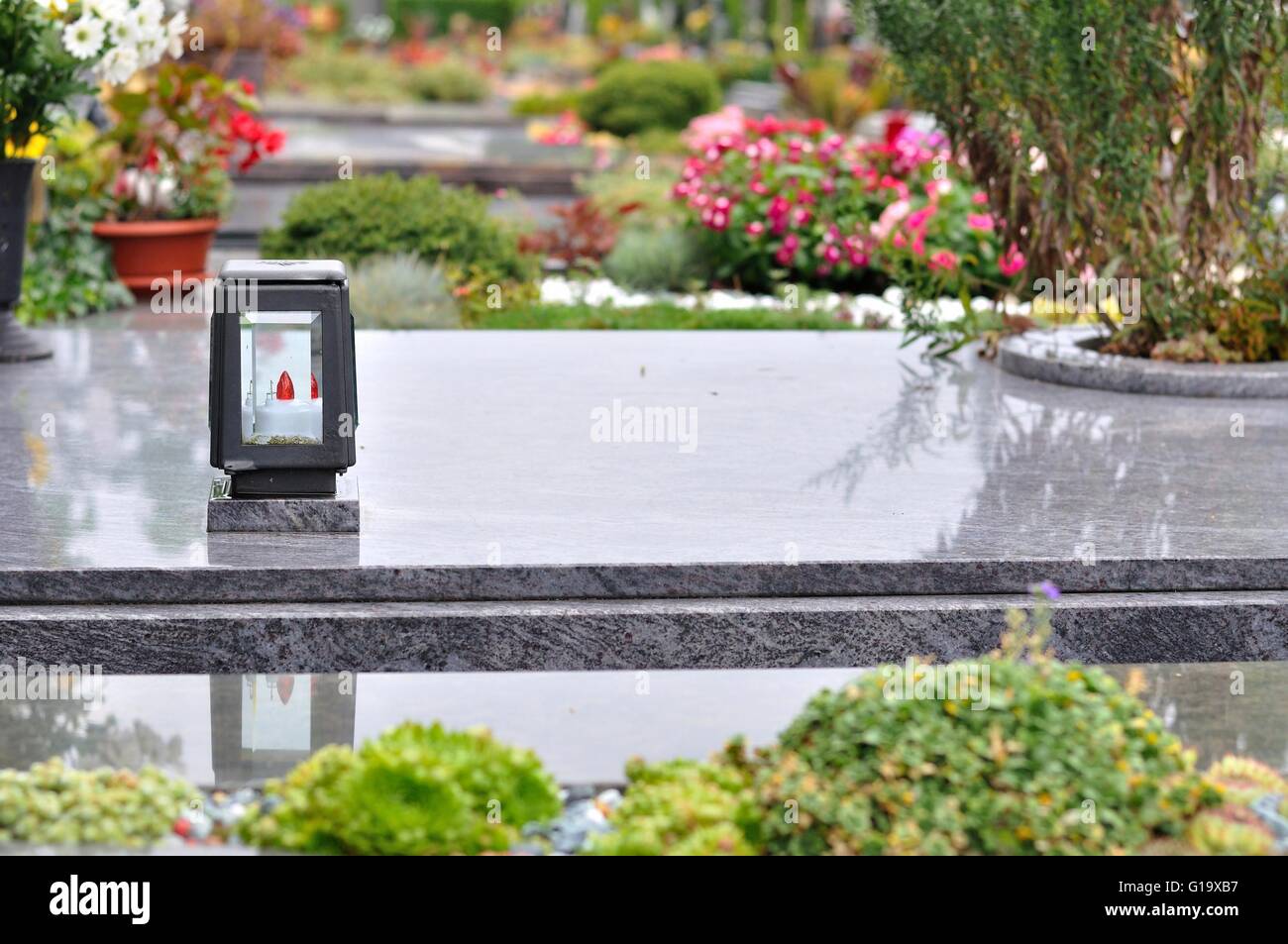 Blumen und Kerzen am Grab im Kirchhof Stockfoto